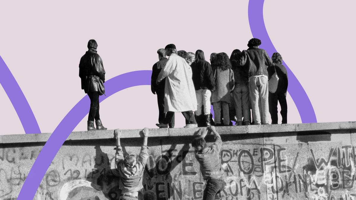 Menschen stehen auf der Berliner Mauer während des Mauerfalls